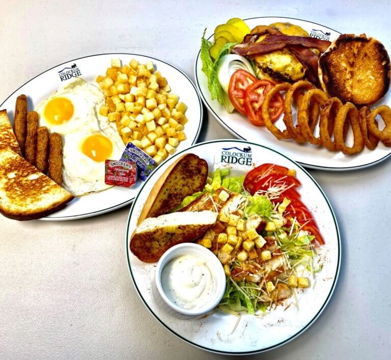 Plates of breakfast, burger with onion rings, and chicken salad