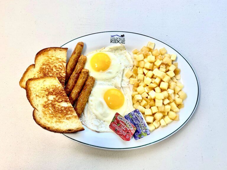 Breakfast plate with eggs, toast, sausage, and potatoes